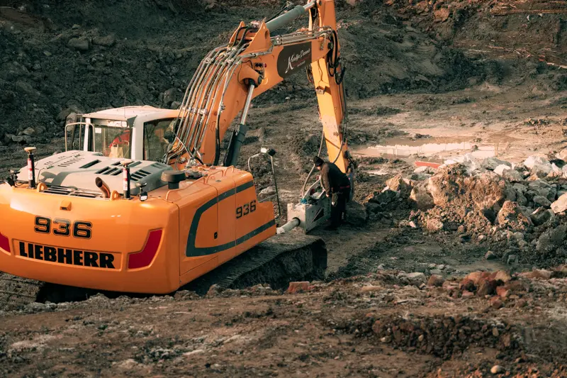 Bild på en gul grävmaskin av märket Liebherr som står i en schaktgrop i Västerås.