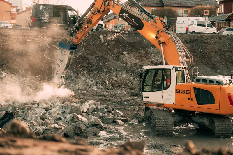En Liebherr bandgrävare knackar sprängsten med en hydraulhammare.