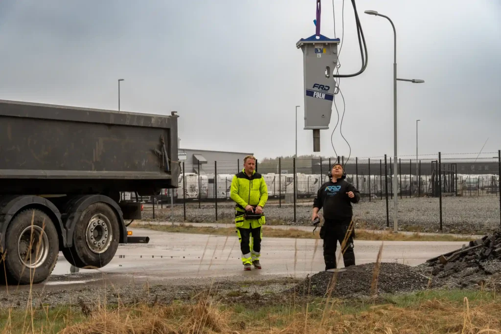 En hydraulhammare upphissad i luften med hjälp av kranbil.