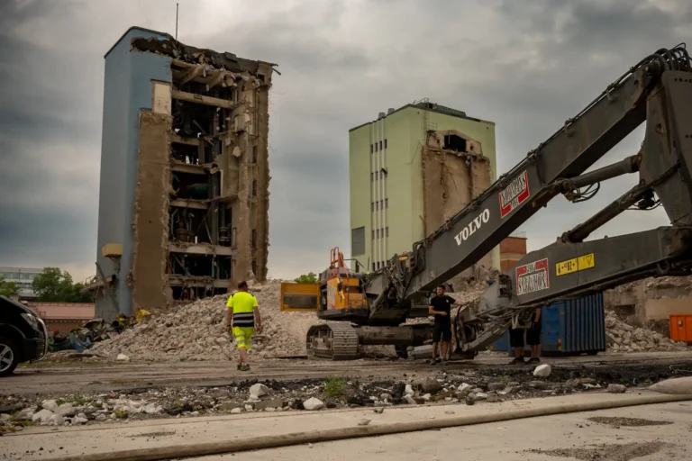 Två byggnader utefter Sågargatan i Uppsala under rivning. Framför dem en Volvo EC480EHR rivningsmaskin.
