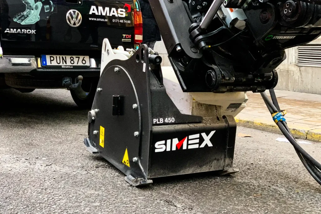 En imponerande Simex PLB450 asfaltsfräs monterad under rotorn på en robust Volvo EWR150E.