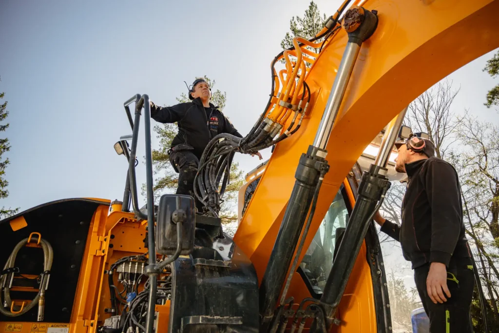 Granskning av grävmaskinens hydraulsystem av AMAS och AP Sprängtjänst personal inför stenspräckning.